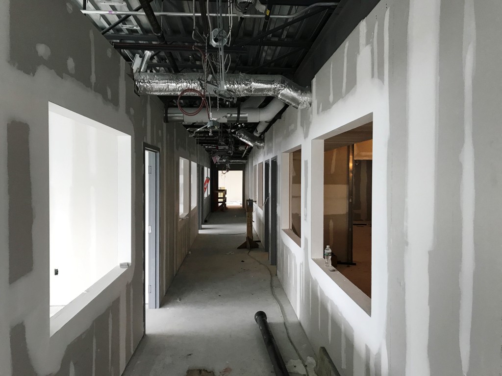Upstairs, wallboard is complete and windows are being hung. This view is from the back of the building looking down the hall way toward the art & science workshops (on the right) and library spaces (on the left).